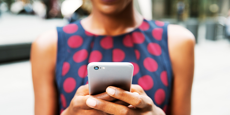 a woman holding a cell phone in both hands in front of her, texting